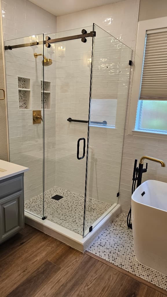 Bathroom remodel in Alamo Ranch San Antonio TX by Raging Bull Contracting — frameless glass walk-in shower with brushed gold fixtures and freestanding white soaker tub