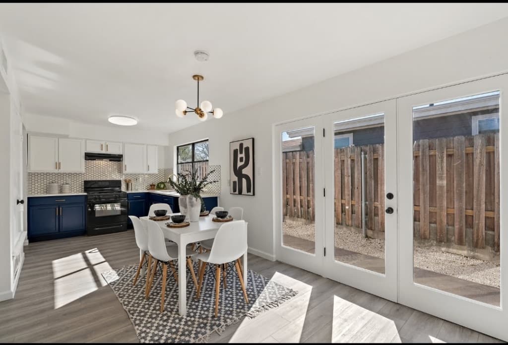 Kitchen remodel in Alamo Ranch San Antonio TX by Raging Bull Contracting — navy blue lower cabinets with white uppers and white hex tile backsplash opening to a dining area with French doors