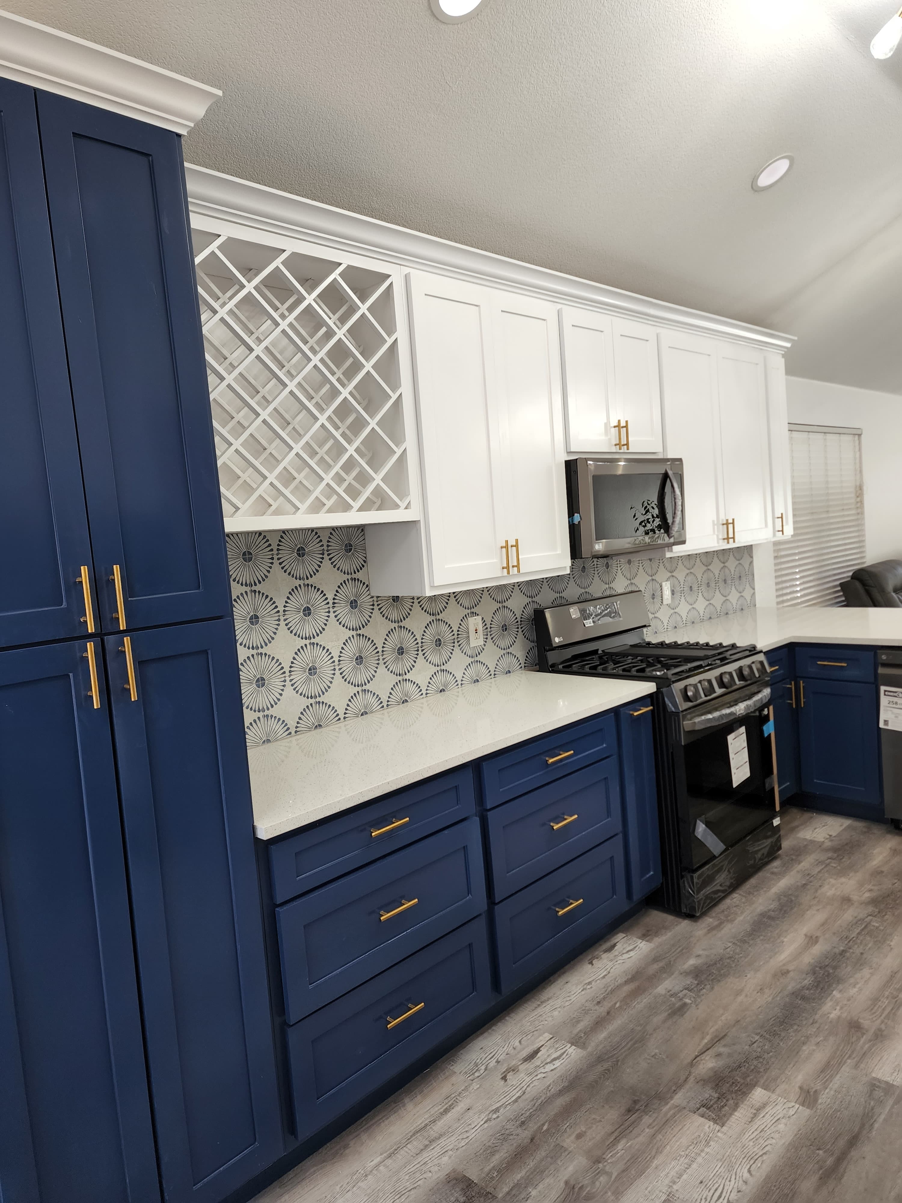 Kitchen remodel in San Antonio TX by Raging Bull Contracting — navy blue Shaker base cabinets with gold hardware, white uppers, built-in wine lattice and black-and-white medallion cement tile floor