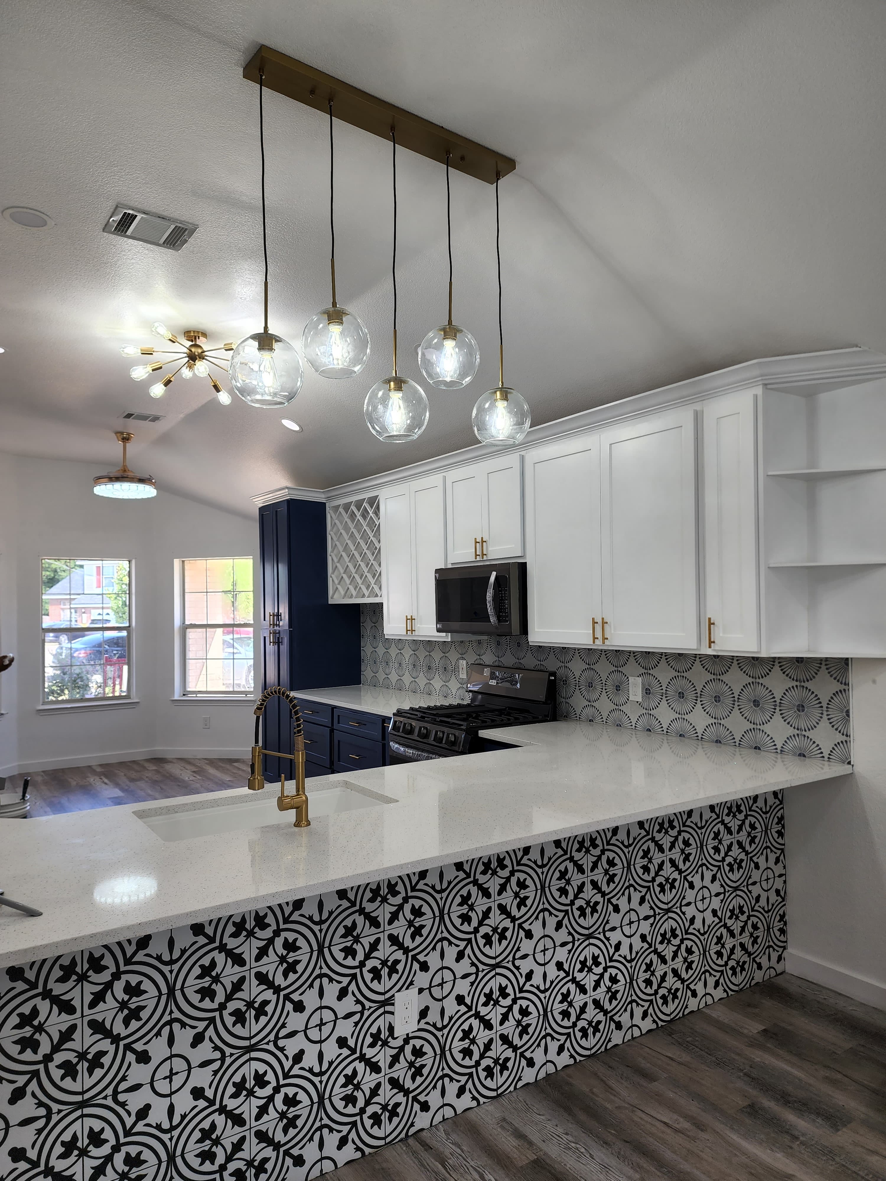 Kitchen remodel in San Antonio TX by Raging Bull Contracting — wide view of navy blue kitchen with brass globe pendant cluster and decorative cement tile floor